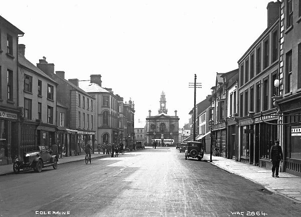 Coleraine - a busy street scene with shop fronts, motor cars, people