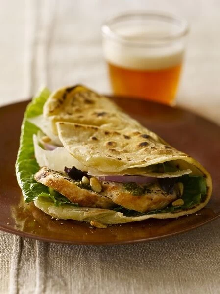 Piadina Genovese, grilled flat bread stuffed with lettuce, red onions, chicken breast, pine nuts, parmesan cheese and pesto sauce, served with a glass of beer
