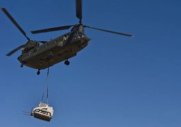 A U. S. Army CH-47 Chinook carries a bulldozer to a drop site
