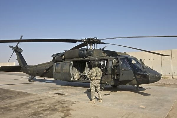 A U. S. Army crew chief stands next to a UH-60 Black Hawk