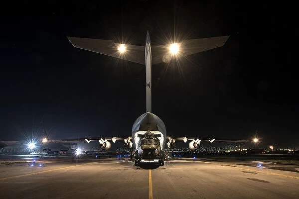 An RAF Chinook helicopter is loaded into a C-17 Globe master