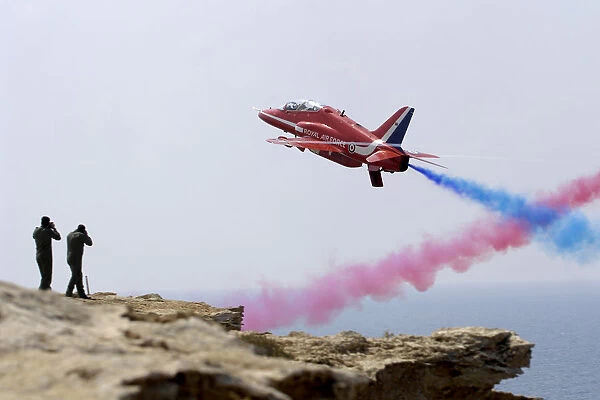 Red Seven of the Red Arrows screams past photographers waiting on a cliff edge