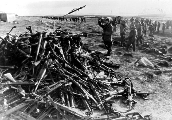 ARGENTINE SOLDIERS THROWING THEIR WEAPONS ONTO A PILE AT PORT STANLEY AFTER SURRENDERING