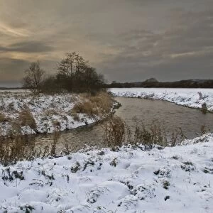 Chalk stream with snow covered banks in early evening, Dorset, Englnad, december