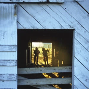 USA, Oregon, Harney County, Cowboys getting ready for work in doorway and backlit
