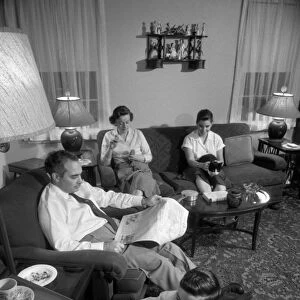 FAMILY, 1957. A family listening to the radio in their living room. Photograph by Warren K