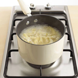 Bowl of fusilli pasta cooking in pan, close-up