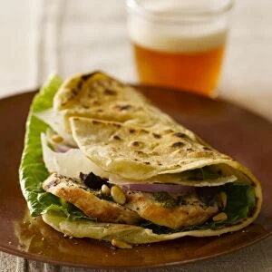 Piadina Genovese, grilled flat bread stuffed with lettuce, red onions, chicken breast, pine nuts, parmesan cheese and pesto sauce, served with a glass of beer