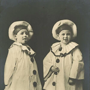 Two boys, dressed as Pierrot, sticking their tongues out (b / w photo)