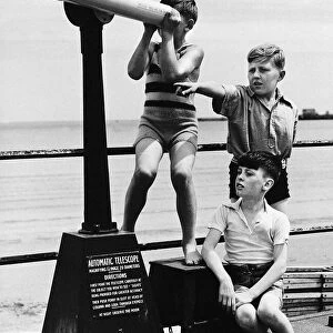 Weymouth boys play on coast with telescope in the Dorset seaside town