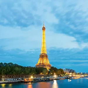 Beautiful Paris view of illuminated Eiffel tower along Seine river at dusk, Paris, France
